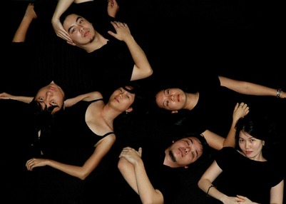 A group of girls and guys lying and posing in black dresses