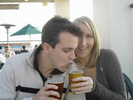 A young guy drinking beer from a girl's glass