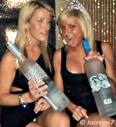 Sexy blondes holding large vodka bottles